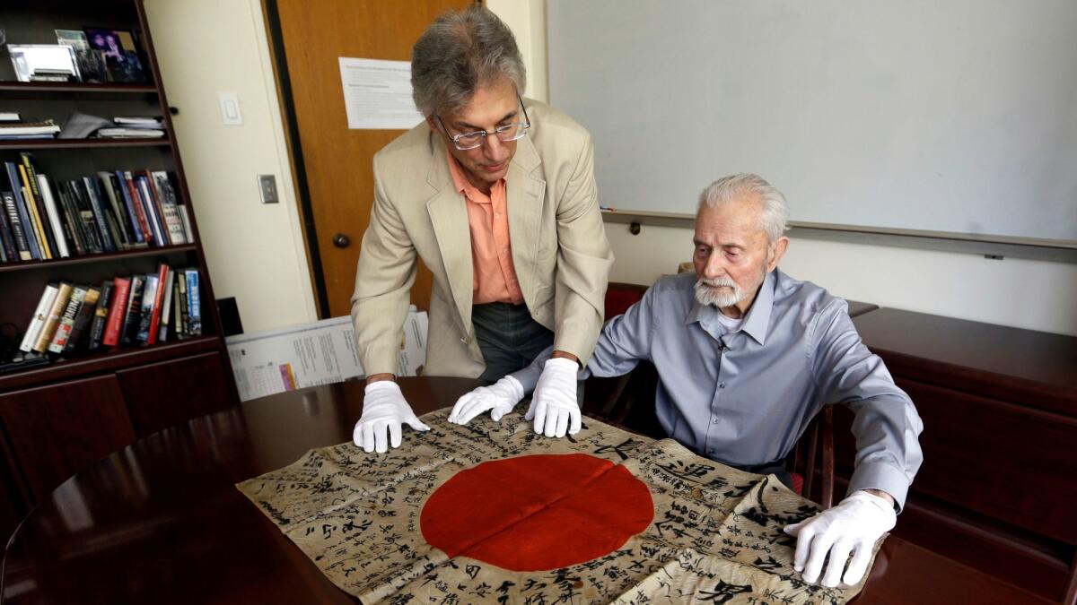World War II veteran Marvin Strombo, right, and Obon Society executives director Rex Ziak inspect a Japanese flag Strombo will return to the family of a Japanese soldier killed in the war.
