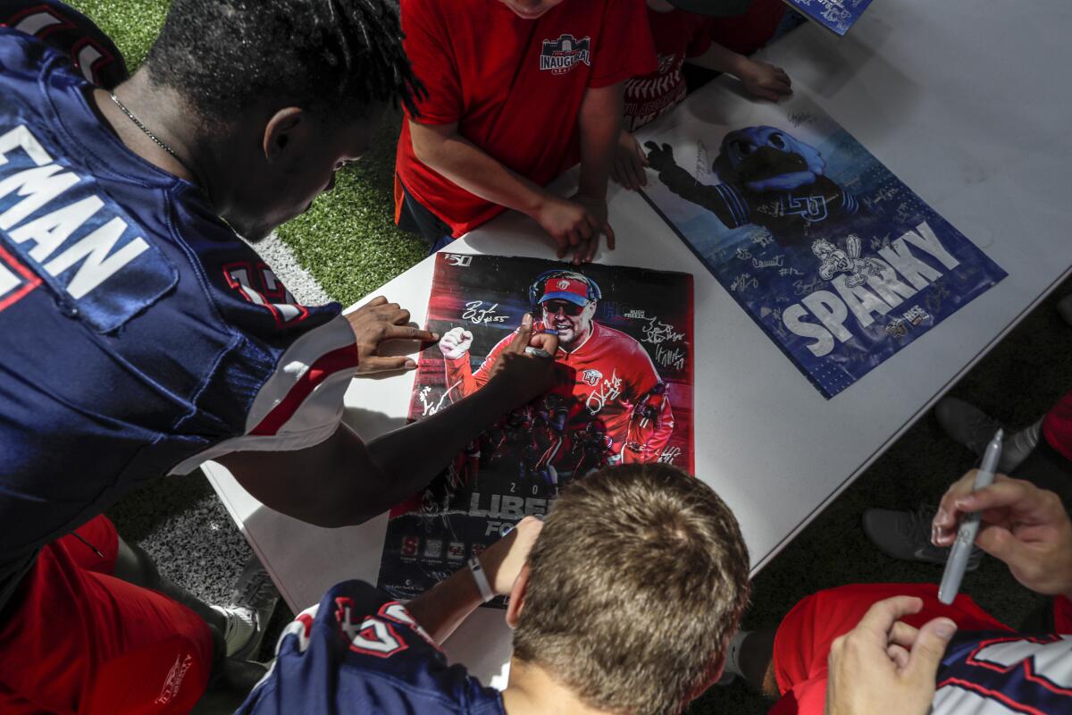 Liberty football players autograph a poster of head coach Hugh Freeze during a fan appreciation event.
