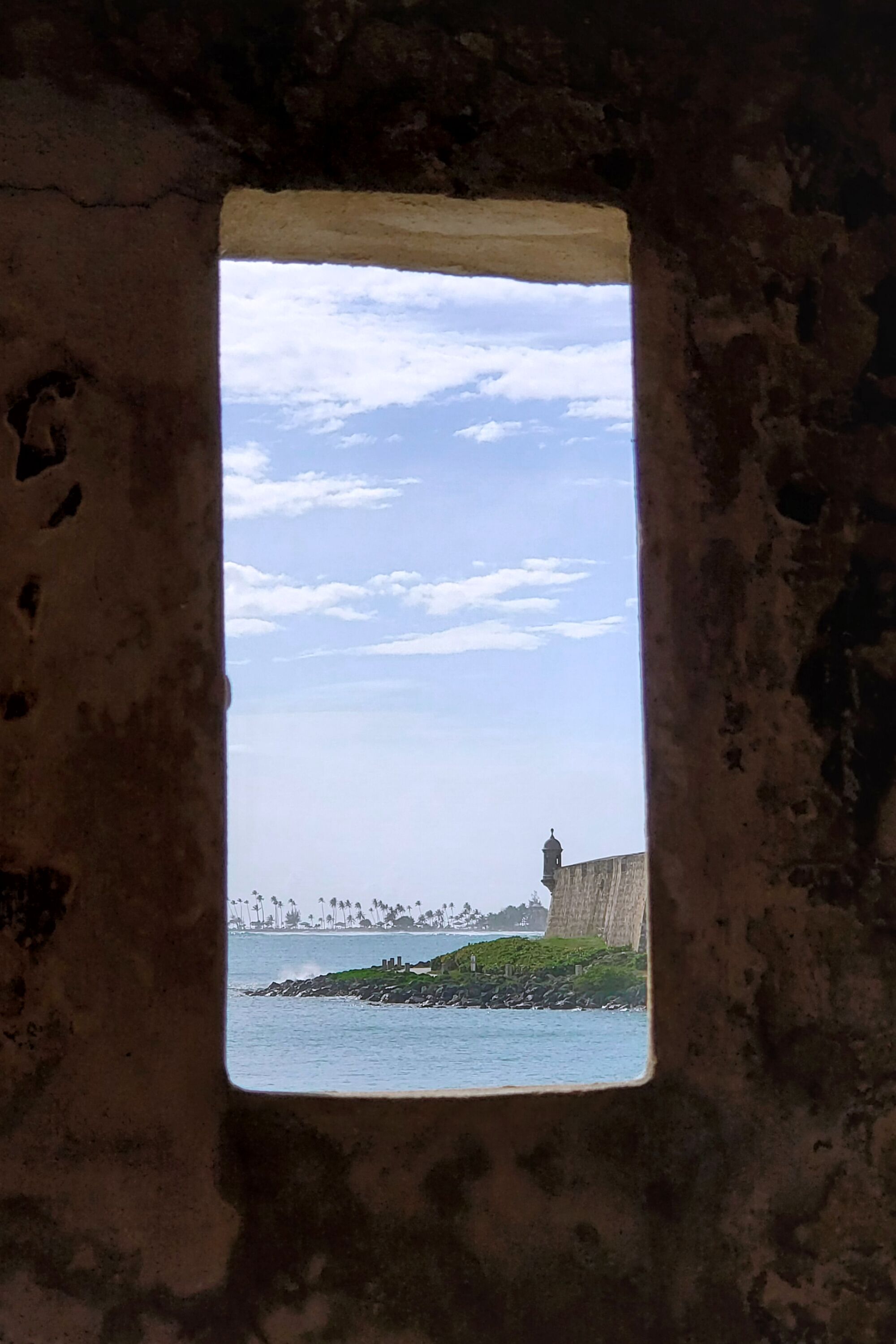 A view through a rugged window of a structure next to the ocean