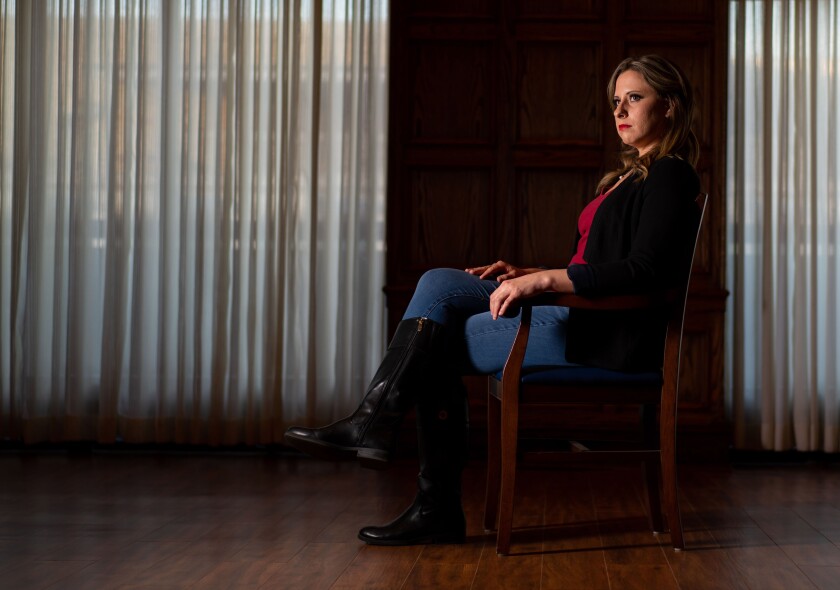 Former Rep. Katie Hill poses seated in profile in front of a black backdrop