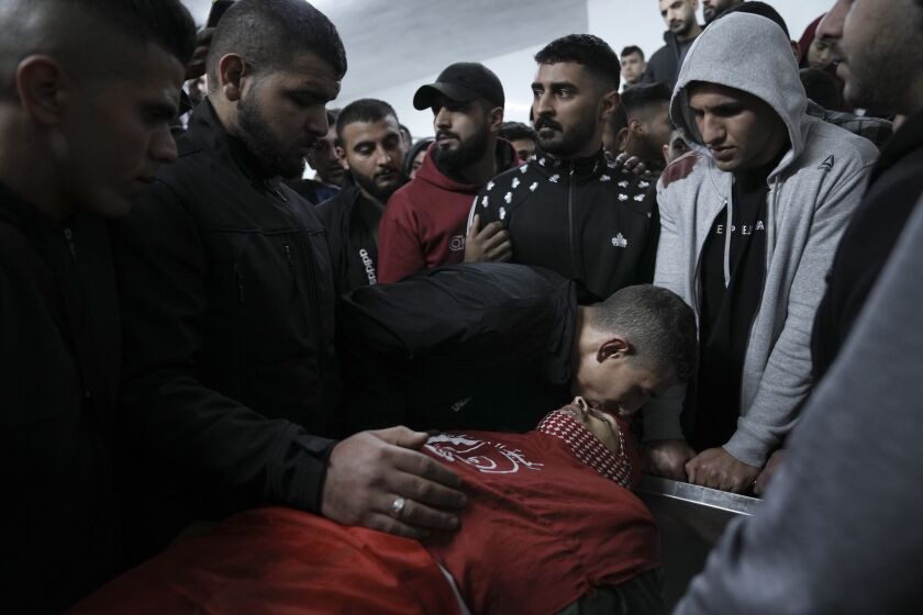 Palestinian mourners gather around the body of Omar Manaa during his funeral in the West Bank refugee camp of Deheishe near the city of Bethlehem, Monday, Dec. 5, 2022. Palestinian health officials say a 22-year-old Palestinian man has been killed by Israeli fire during a military raid in the occupied West Bank. The army said it opened fire after a crowd attacked soldiers with stones and firebombs. (AP Photo/Mahmoud Illean)