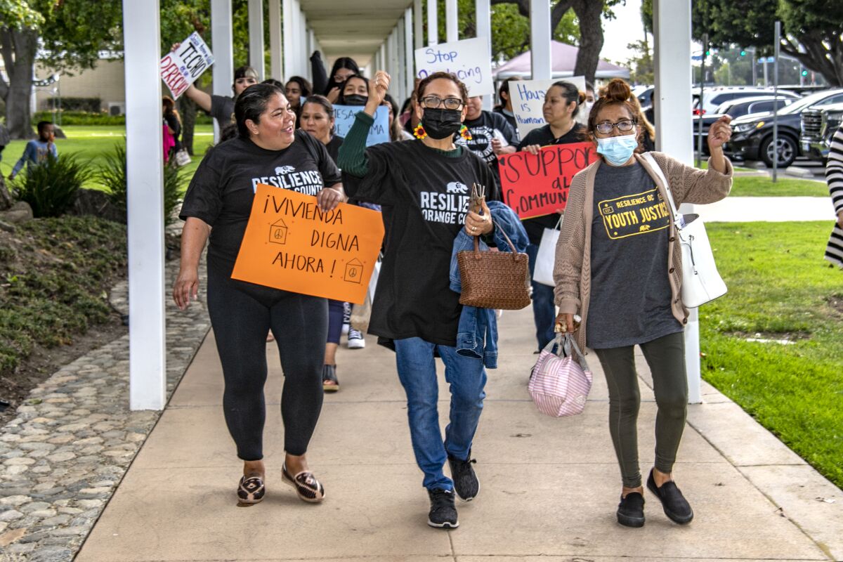 Demonstrators carry Spanish-language signs as they march to the Costa Mesa City Council meeting.