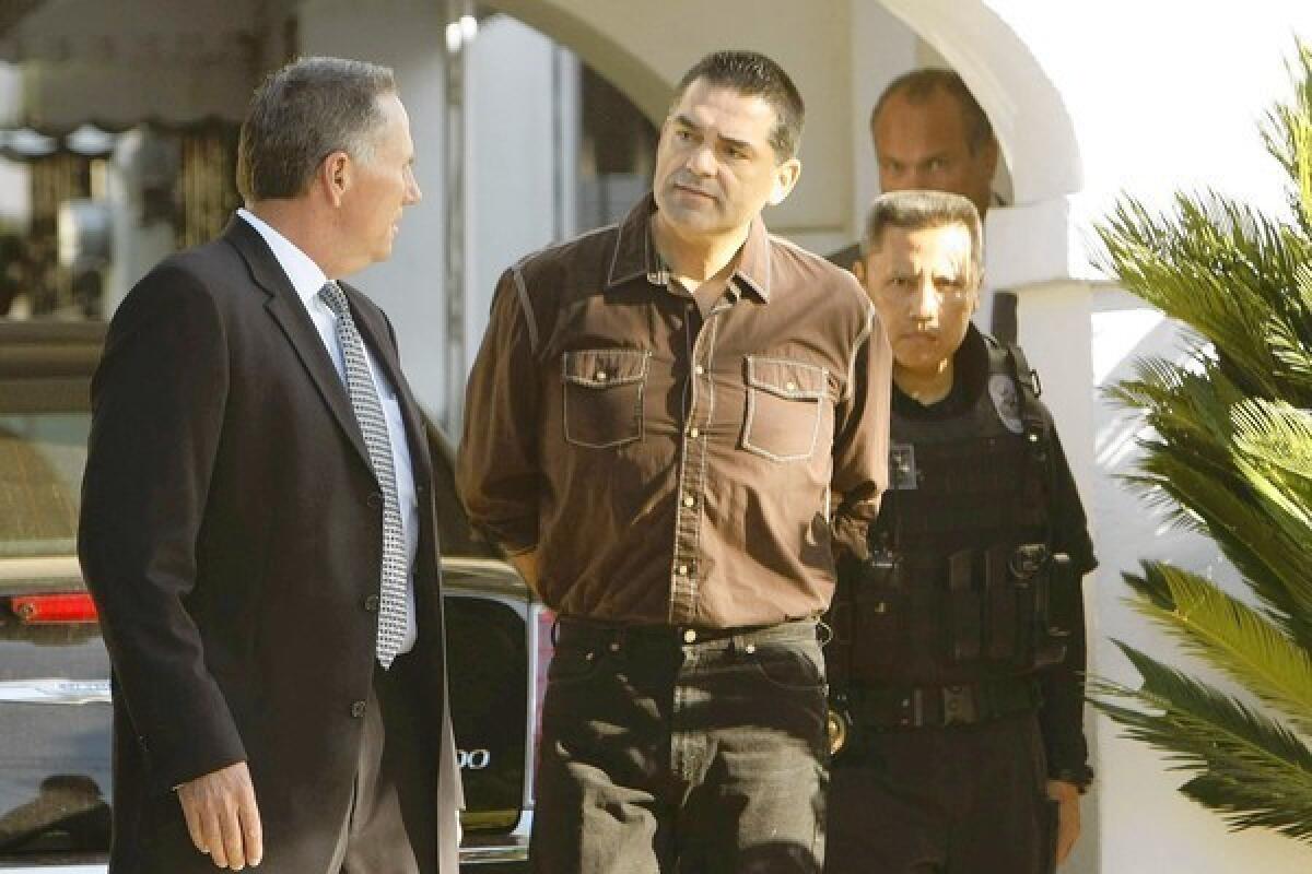 Los Angeles County Assessor John Noguez is taken into custody by investigators with the Los Angeles County district attorney's office outside his Huntington Park home. The assessor is accused of taking bribes from a prominent property tax consultant.