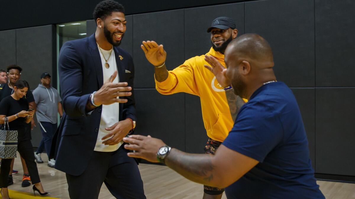 New Lakers big man Anthony Davis, left, is greeted by LeBron James and James' friend and business partner Randy Mims after a news conference Saturday in El Segundo.