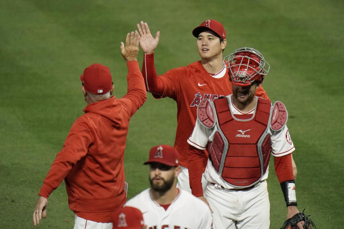 The Angels' Shohei Ohtani, top, gives manager Joe Maddon a high-five 