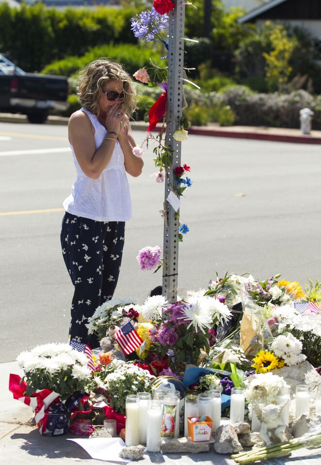 A woman visits a memorial Thursday near the intersection of 15th Street and Michael Place in Newport Beach, where an 8-year-old boy was struck and killed by a trash truck the day before.