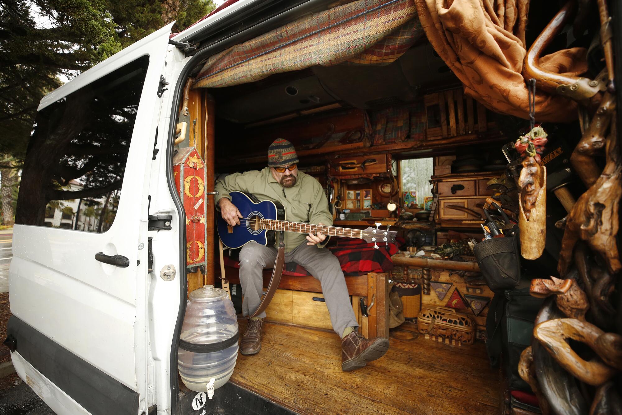 Musician and carpenter Doug Jaffe plays his guitar as he composes music in this van parked along East Beach in Santa Barbara.