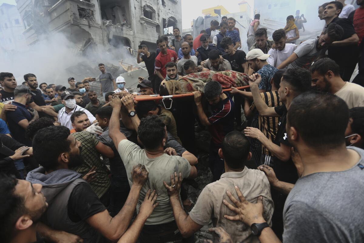 Palestinos retiran un cuerpo de entre los escombros de un edificio tras un ataque aéreo israelí 