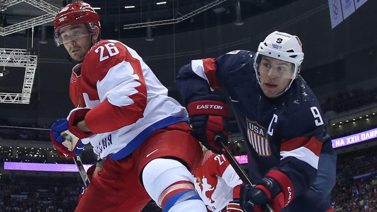 Russia defenseman Slava Voynov, left, battles for position in front of the net with U.S. forward Zach Parise during the United States' 3-2 victory in a preliminary round match at the Sochi Winter Olympic Games on Feb. 15, 2014.