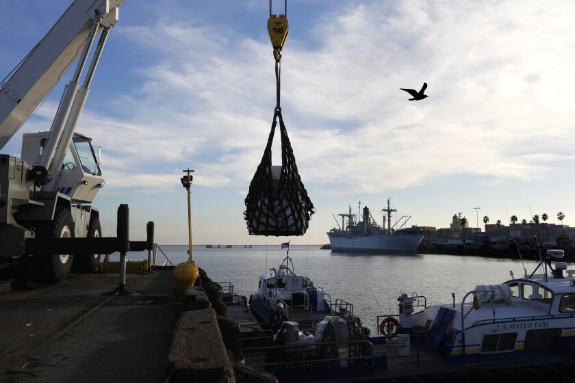 SAN PEDRO-CA-JANUARY 10, 2022: Orders from Harbor Ship Supply, a 90-year-old family owned ship chandler business in San Pedro, are crane lifted by U.S. Watertaxi onto a boat at the Port of Los Angeles, who will then deliver to the ships. (Christina House / Los Angeles Times)