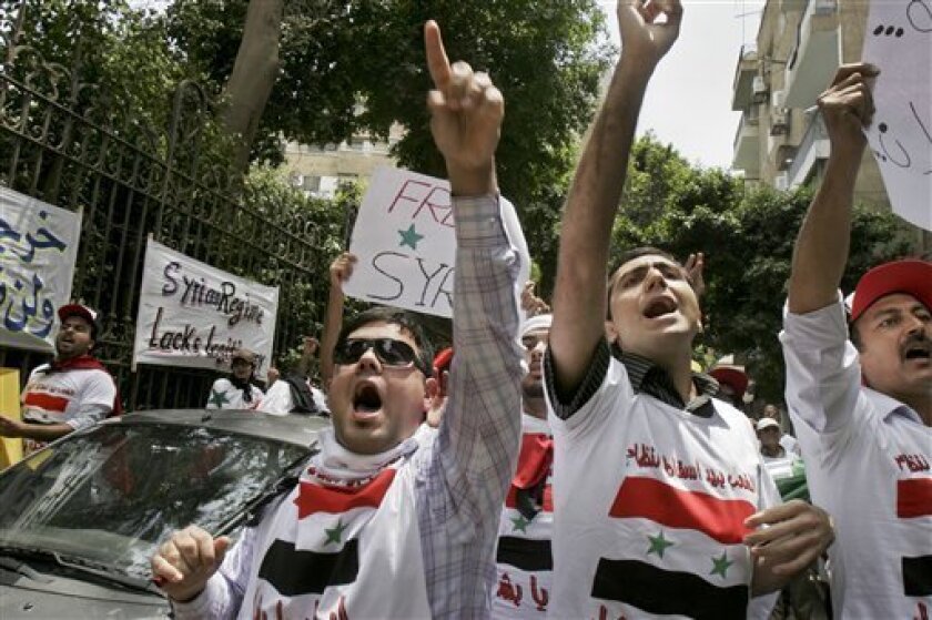 Demonstrators rally against the Syrian regime's crackdown on protesters, outside the Syrian embassy in Cairo, Egypt Tuesday, May 10, 2011. Syrian troops backed by tanks entered several southern villages near the flashpoint city of Daraa on Tuesday, according to an activist, as the Syrian government pressed its efforts to end a nationwide uprising. Writing in Arabic on t-shirts showing the Syrian flag reads "The people want to topple the regime". (AP Photo/Mohammed Abu Zaid)