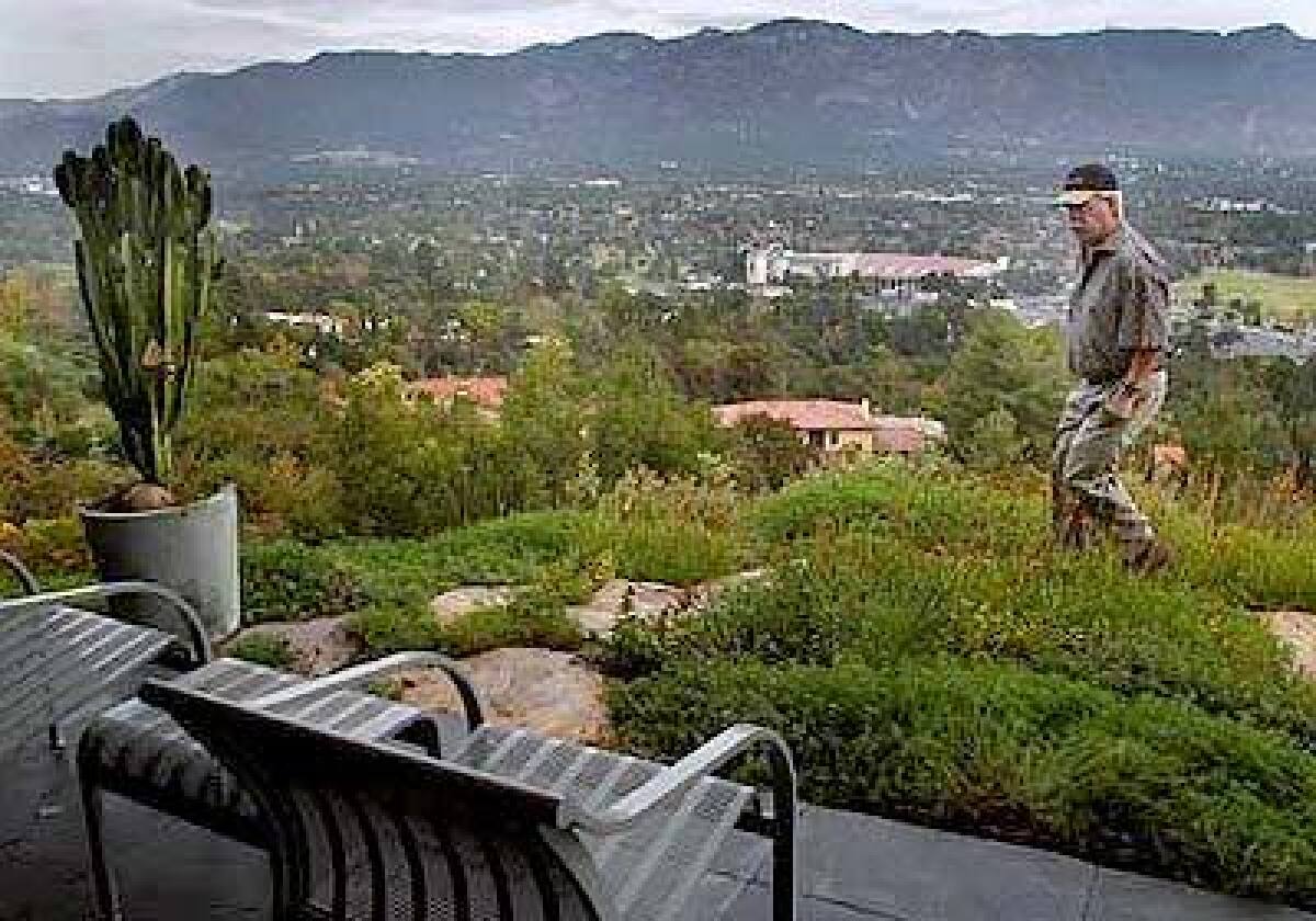 Alex Moseley strolls through a meadow of orange-tipped bulbines at his Pasadena home, which overlooks the Rose Bowl.