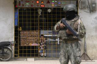 A boy watches from behind the bars of an open electronics store as a soldier stands guard at a security check point placed by the army in Duran, across a bridge from Guayaquil, Ecuador, Monday, Aug. 14, 2023. Ecuador's president declared a state of emergency in some areas after a presidential candidate was killed at a rally ahead of snap elections, set for Aug. 20, after President Guillermo Lasso dissolved the National Assembly to avoid being impeached. (AP Photo/Martin Mejia)