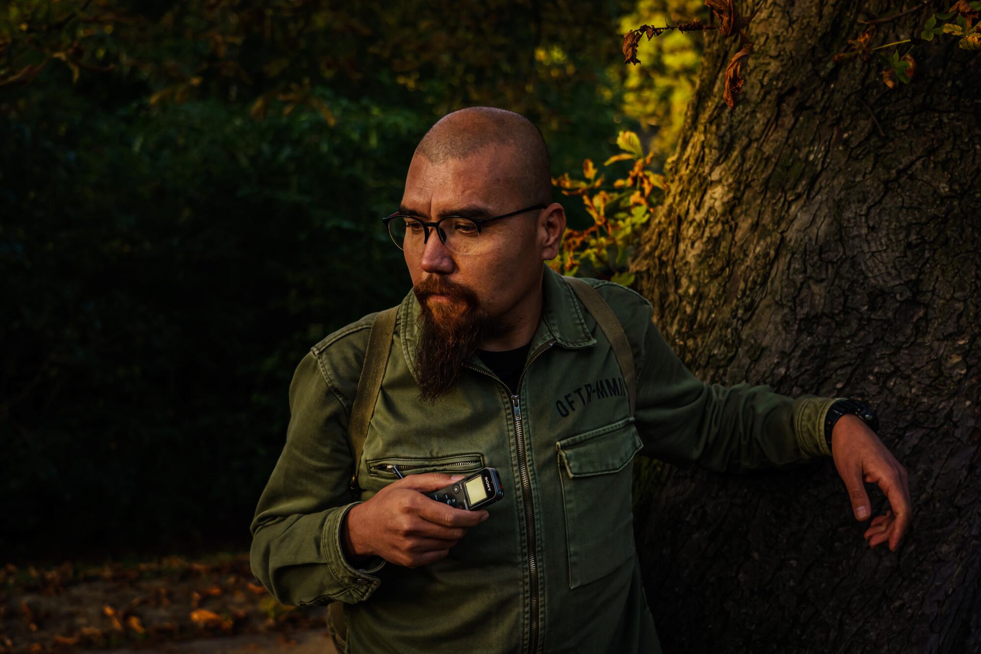 A man holds a digital recorder in park