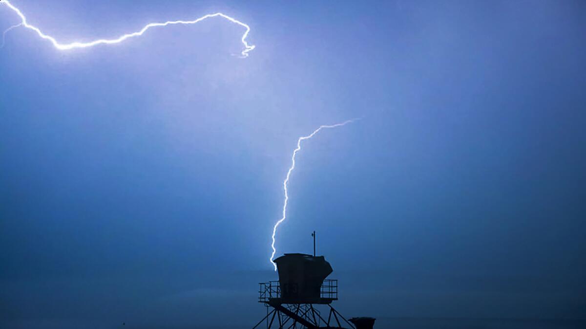A lifeguard tower is illuminated by a lightning strike.