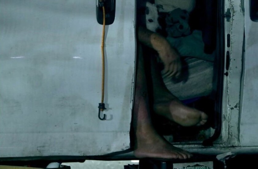 A man's hand and feet are visible through the open door of a shelter