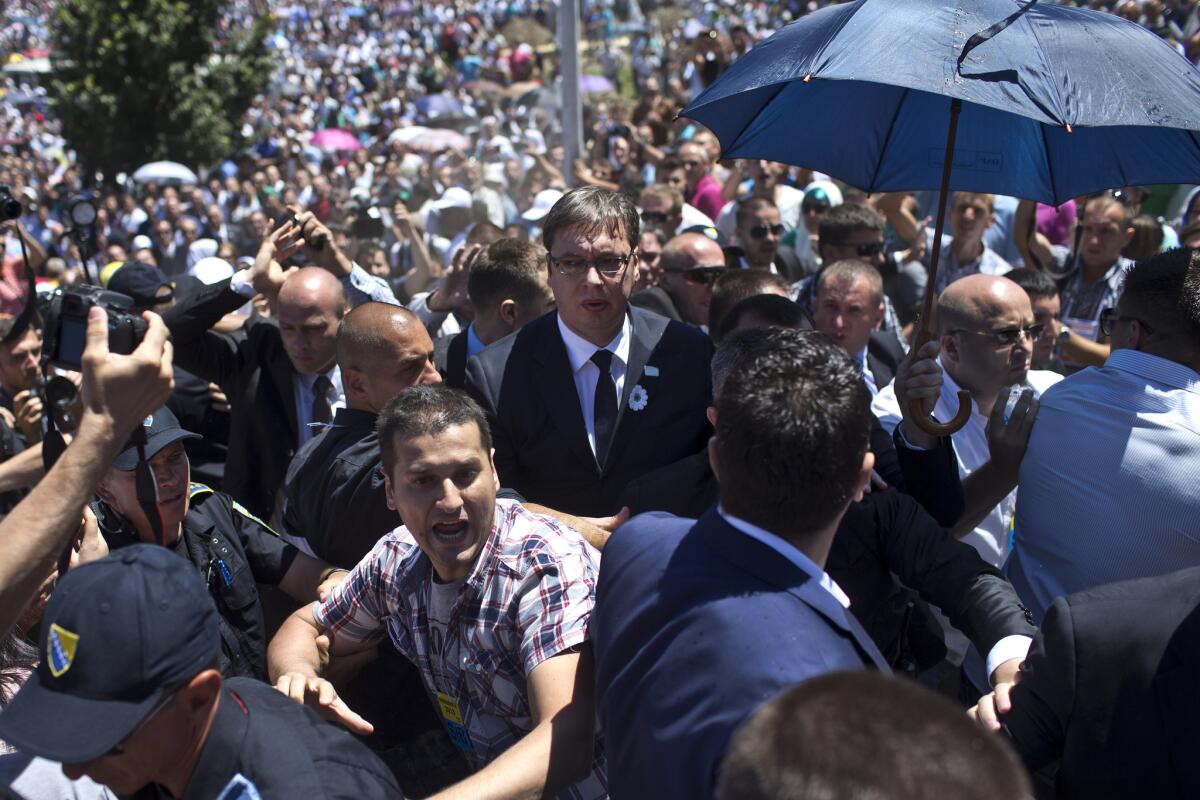 Serbian Prime Minister Aleksandar Vucic, center, makes his way through a hostile crowd during commemoration ceremonies of the Srebrenica massacre.