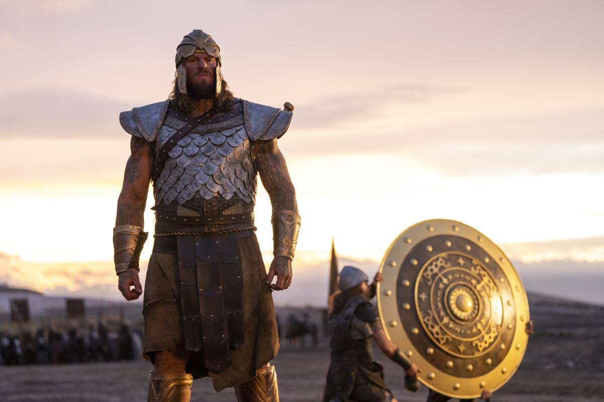 A elephantine antheral successful metallic and leather armor lasting successful a tract arsenic 2 smaller radical transportation distant a aureate shield.