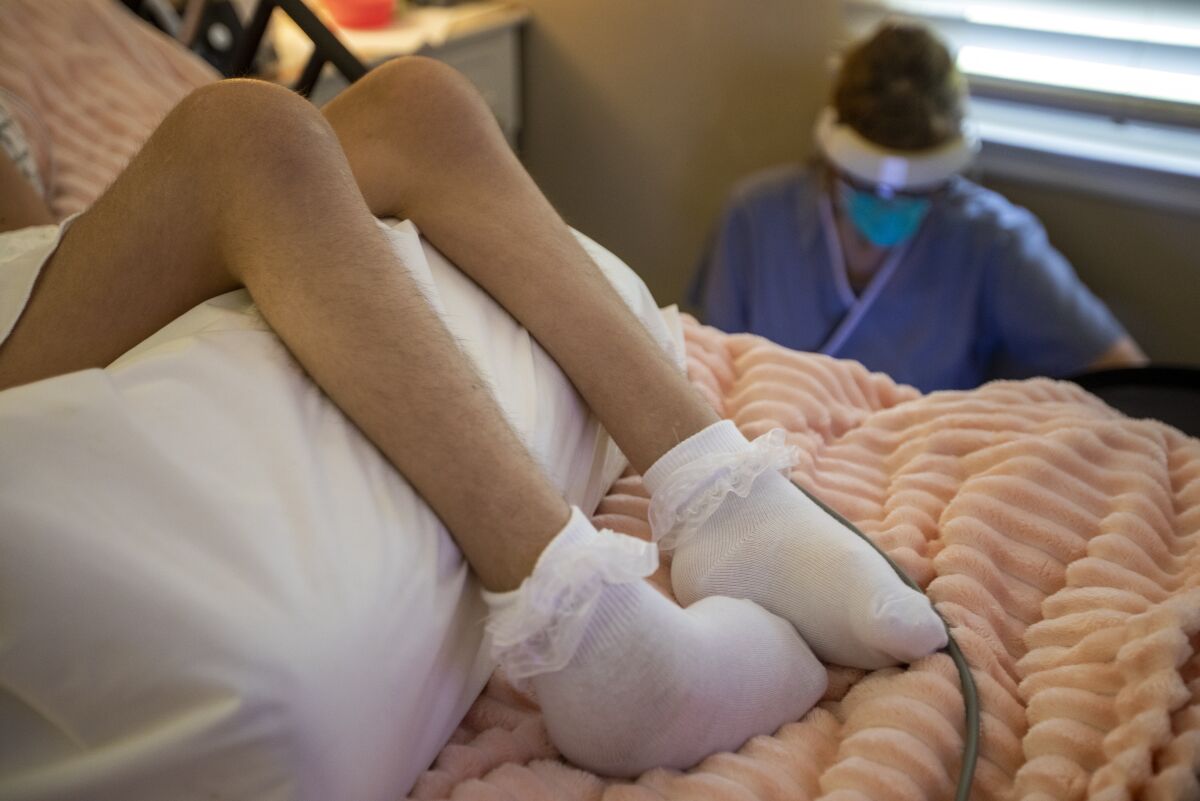 A pediatric hospice nurse works on her laptop bedside while her patient rests in Whittier in 2021.