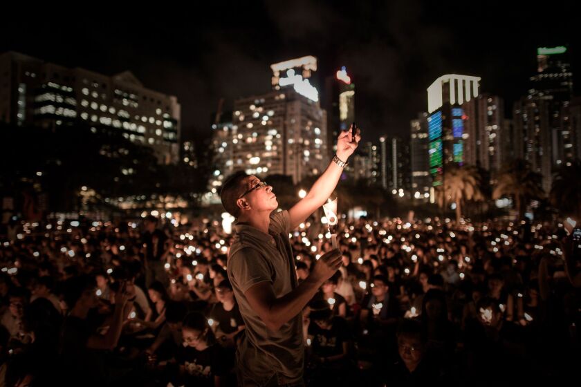 A man takes a picture with his phone as others hold candles at a vigil in Hong Kong to commemorate the 25th anniversary of the Tiananmen Square massacre in Beijing.