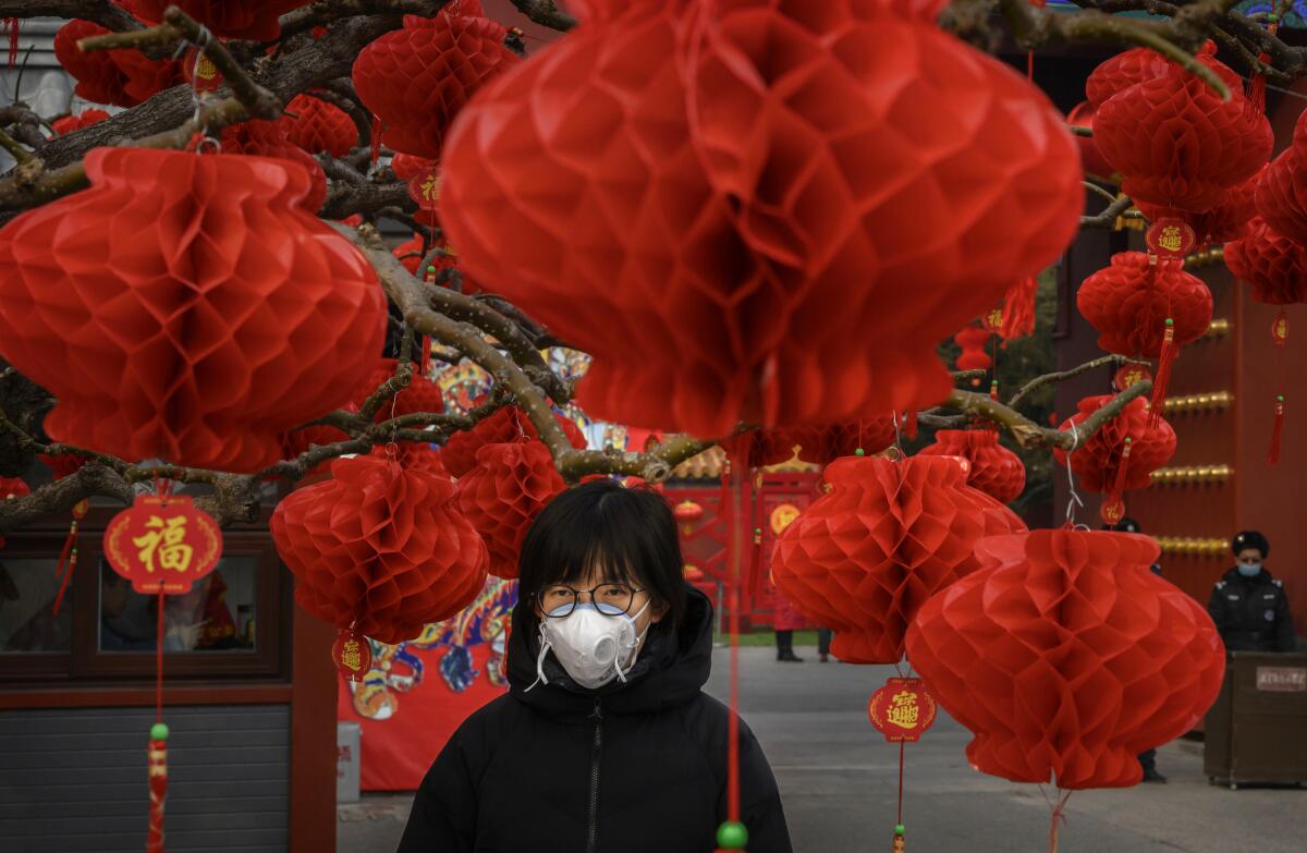 A woman stands near decorations marking the Lunar New Year holiday in Beijing on Monday.