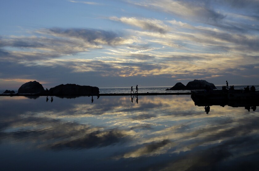 People walk along a path at Sutro Baths, once the world's largest indoor swimming pool facility, in San Francisco on Feb. 16. California is having another day of unseasonable warmth before a low-pressure system brings rain and snow.