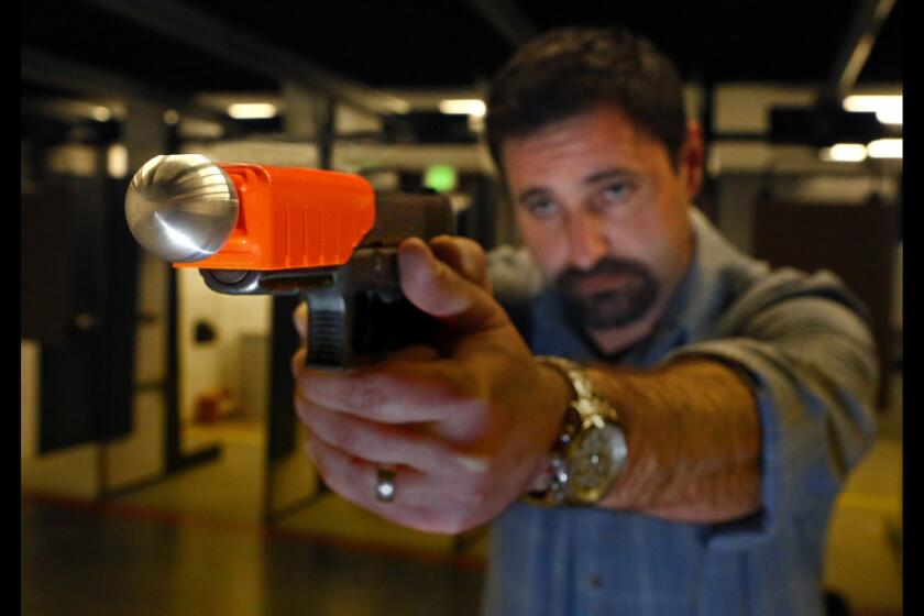 Christian Ellis of Alternative Ballistics demonstrates his company's "less lethal" weapon at the San Diego Firearms Training Center in Poway, Calif. When fired, the pistol's bullet is captured inside a metal sphere, which is propelled at a lower velocity than a bare bullet.