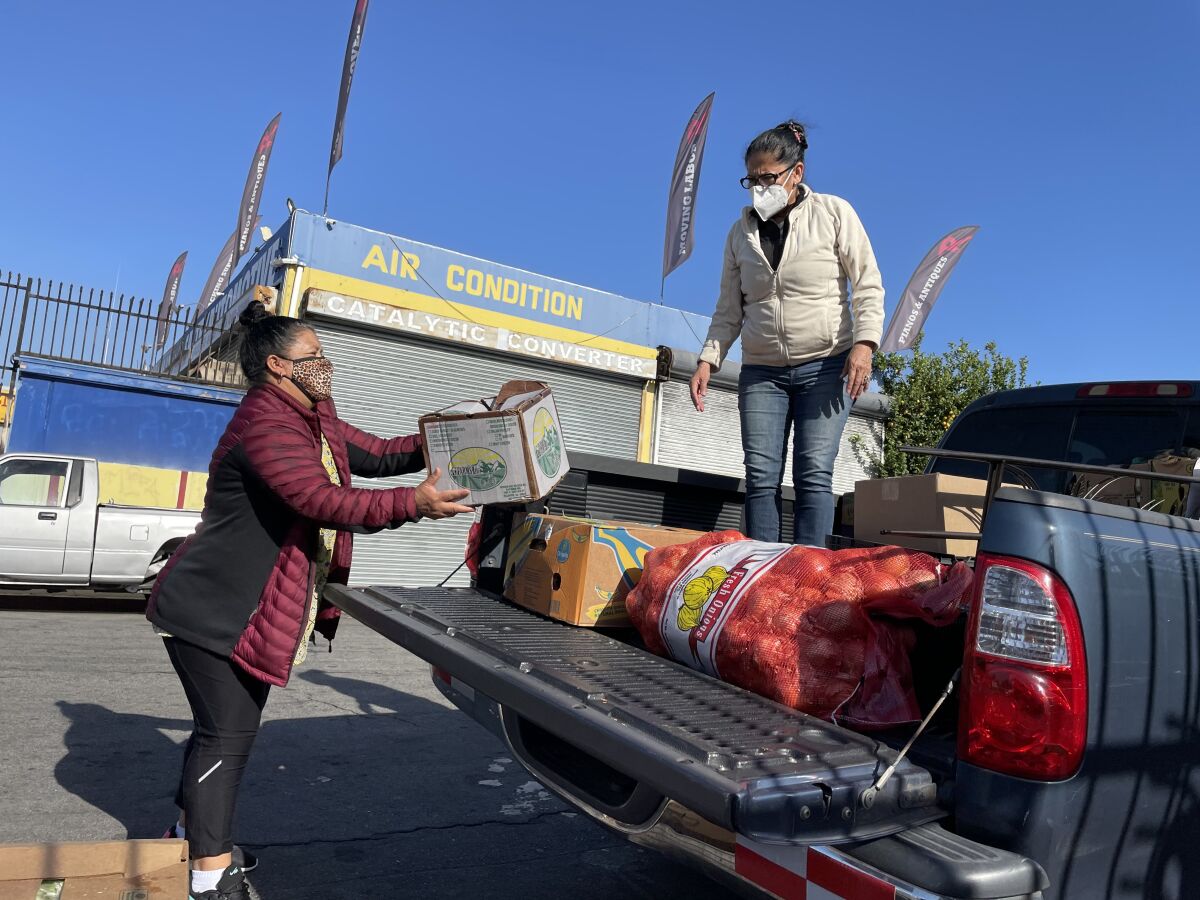 Daysi Villanueva y Ana González (derecha) cargan su camioneta con vegetales y frutas adquiridos en Monte Sión Center.