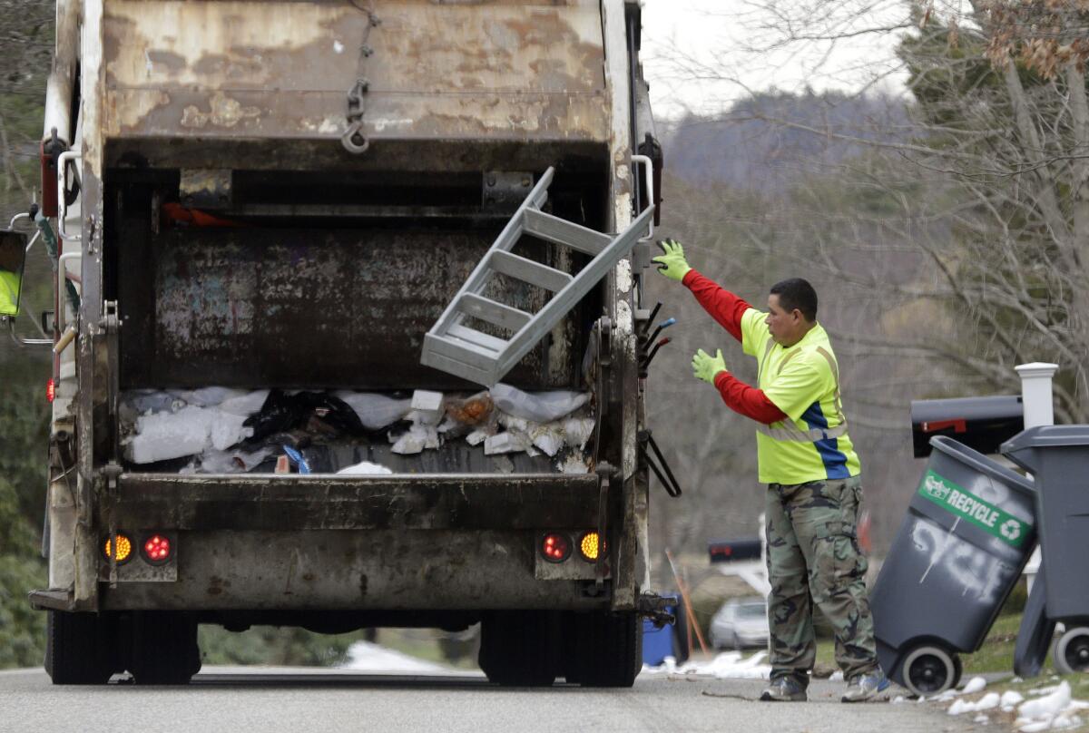 A sanitation worker throws a stepladder into his truck in North Andover, Mass., on March 23. On Friday, April 1, the government issued the U.S. jobs report for March.