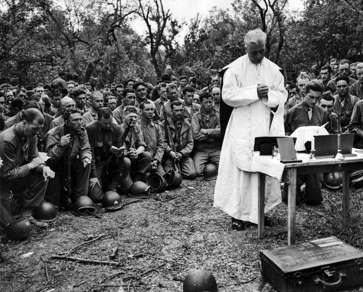 April 25, 1943: Father Marius S. Chataignon, Army Chaplain, conducts Easter Sunday Mass for U.S. troops close to front lines in Tunisia.