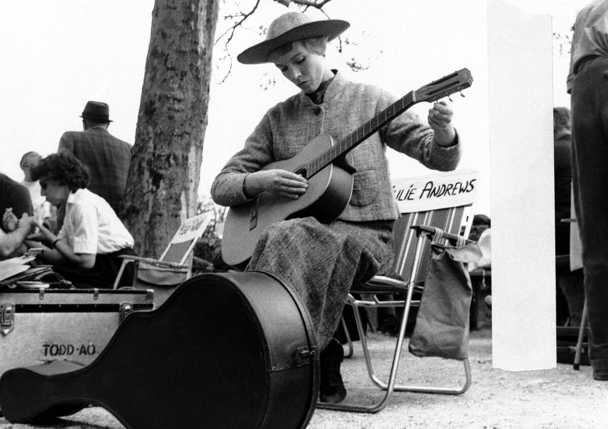 black-and-white photo of a woman tuning a guitar