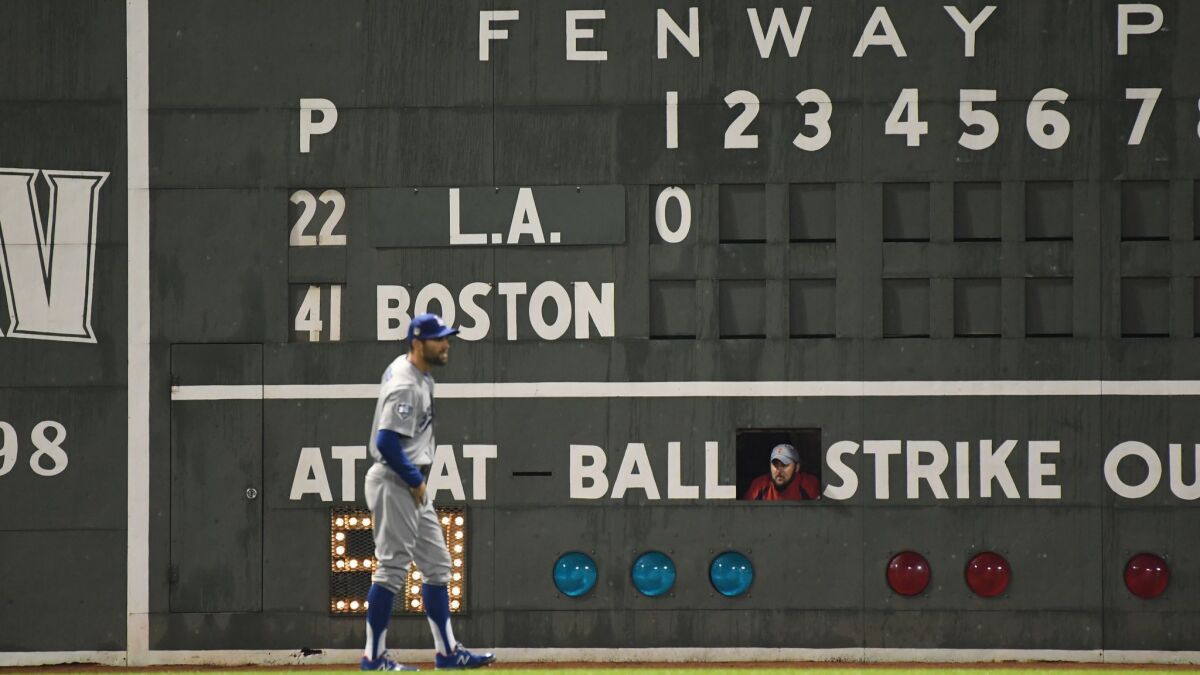With a Fenway Park scoreboard handler looking on, the Dodgers' Chris Taylor gets into position in the first inning of Game 1 of the World Series in Boston.