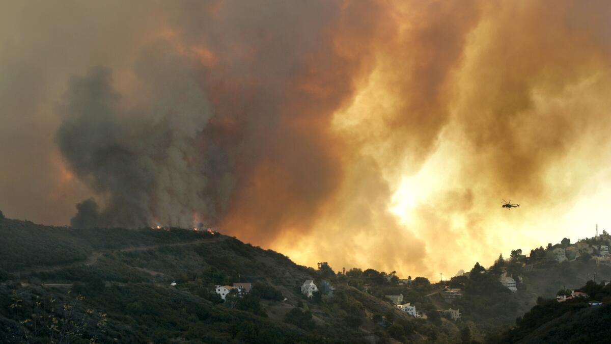 A helicopter flies toward a massive smoke plume rising from a wildfire in Malibu's Latigo Canyon in November.