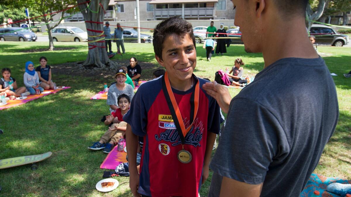 Jose Serrano, right, presents Mohammad Zahid a medal for participating in the World Cup Summer Soccer Camp in Westminster on Aug. 23.