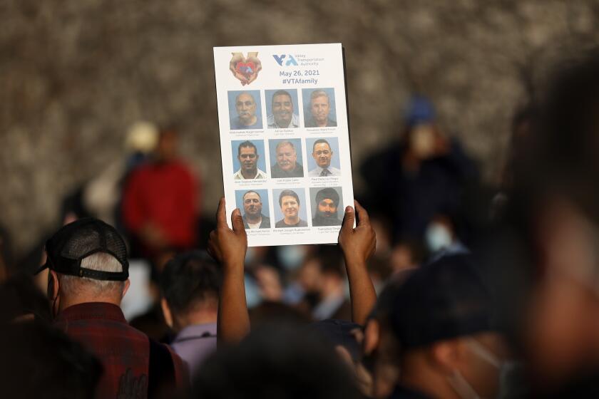 SAN JOSE, CALIFORNIA - MAY 27: A mourner hols a sign with images of the nine Santa Clara Valley Transportation Authority (VTA) light rail yard shooting victims during a vigil at San Jose City Hall on May 27, 2021 in San Jose, California. Hundreds attended a vigil for the nine people were killed when a VTA employee opened fire at the VTA light rail yard during a shift change on Wednesday morning. (Photo by Justin Sullivan/Getty Images)