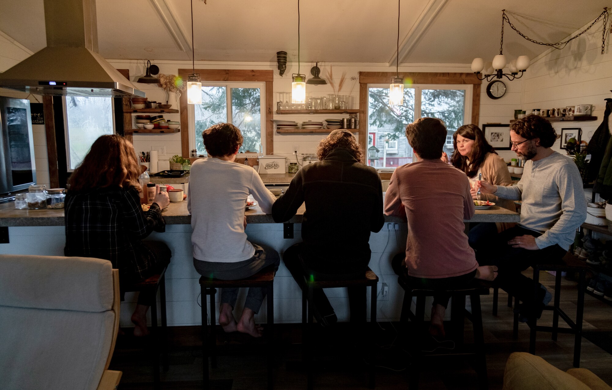 Six people sitting on stools and eating at a kitchen counter