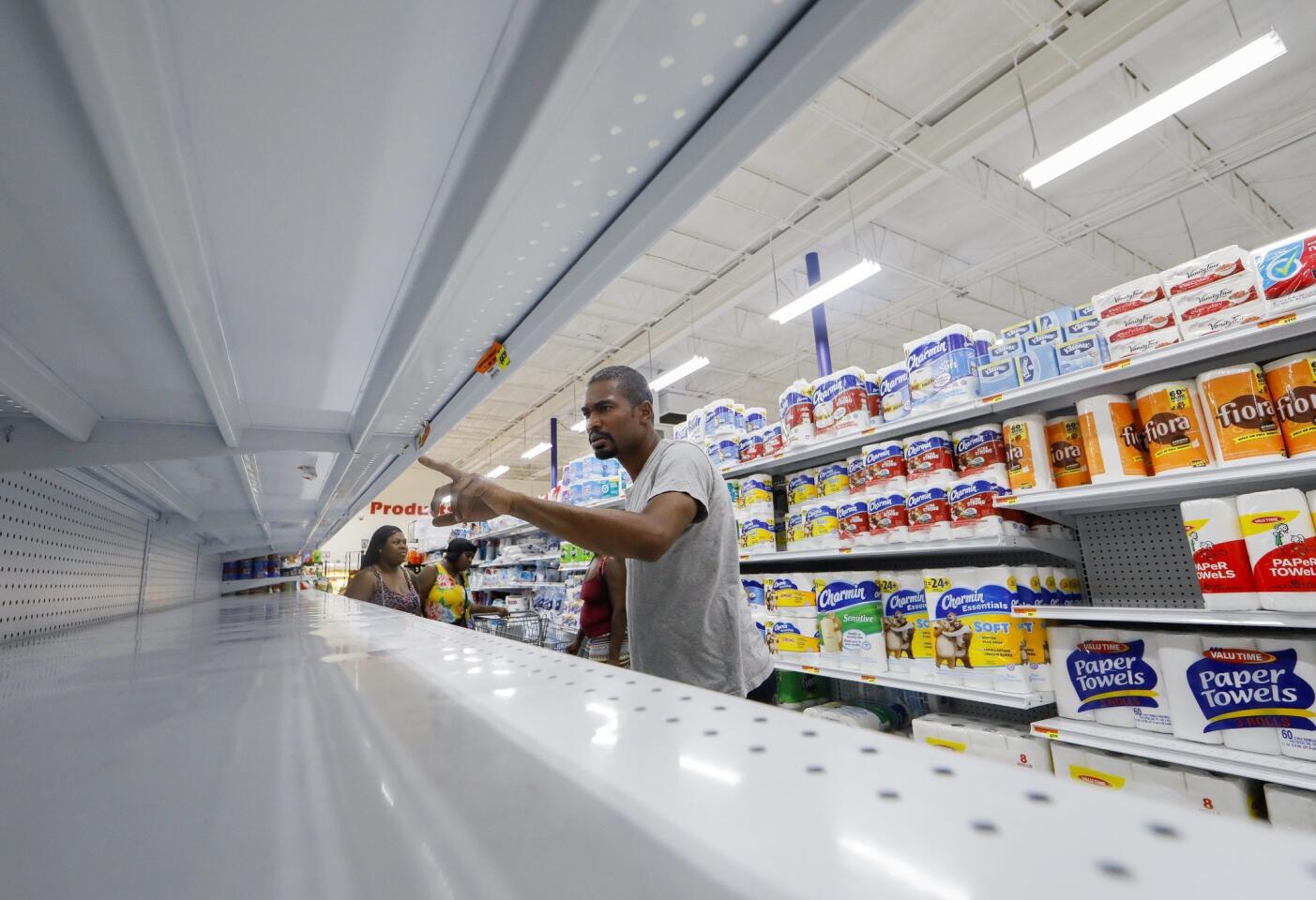 A shopper searches the sparse water shelves at the Presidente Supermarket in the Little Haiti neighborhood ahead of the expected arrival of Hurricane Irma in Miami on Sept. 7, 2017.