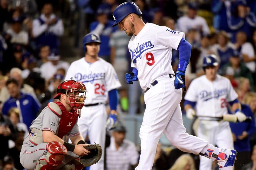 Dodgers catcher Yasmani Grandal scores a run in front of Cincinatti Reds catcher Tucker Barnhart from his solo homerun to take a 3-1 lead during the fifth inning at Dodger Stadium on Wednesday.