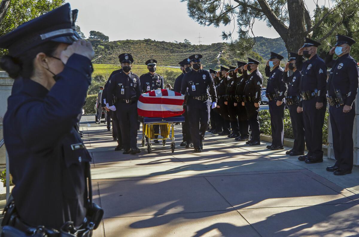Pallbearers carry the casket of LAPD Officer Fernando Arroyos with police officers lined up at each side.