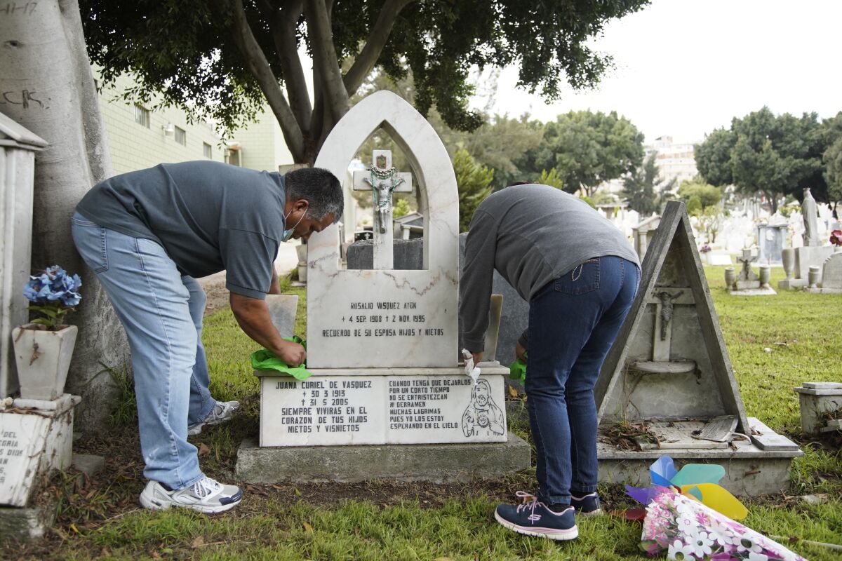 The grandson of Rosalio Vasquez cleans her tombstone at Municipal Cemetery Number 3 on Oct. 24 in Tijuana, Baja California.