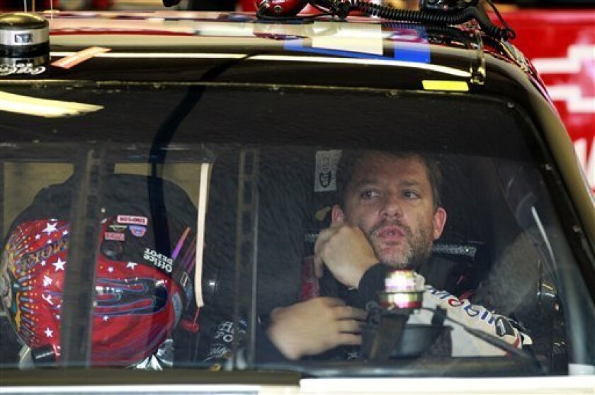 Tony Stewart adjusts his safety equipment before going out on the track during practice for the NASCAR Sprint Cup Series Coke Zero 400 auto race at Daytona International Speedway, Thursday, July 5, 2012, in Daytona Beach, Fla. (AP Photo/John Raoux)