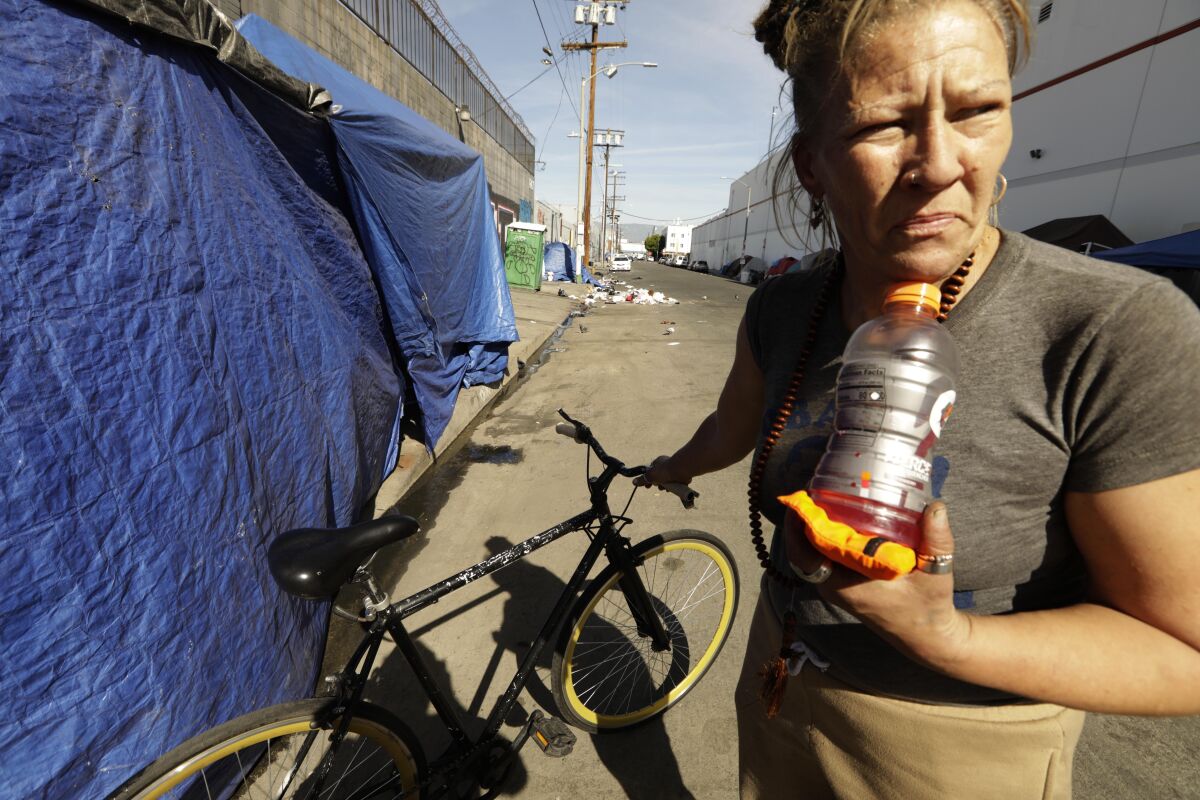 A person stands next to a bike and a tarp
