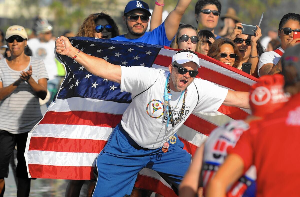 Fans cheer on athletes from the men's division of the triathlon during the Special Olympics in Long Beach on Monday.