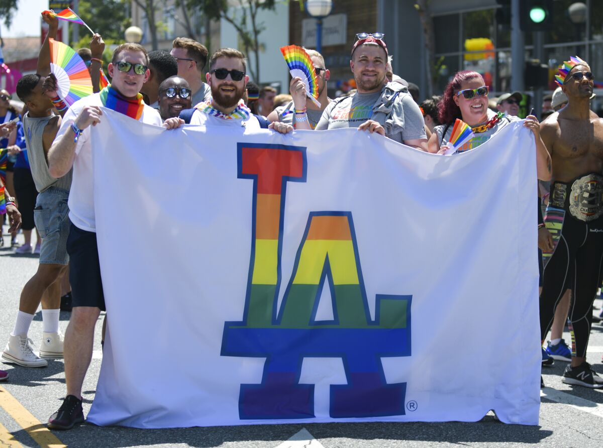 Dodgers supporters hold a flag with the team's logo in rainbow colors during a Pride event.