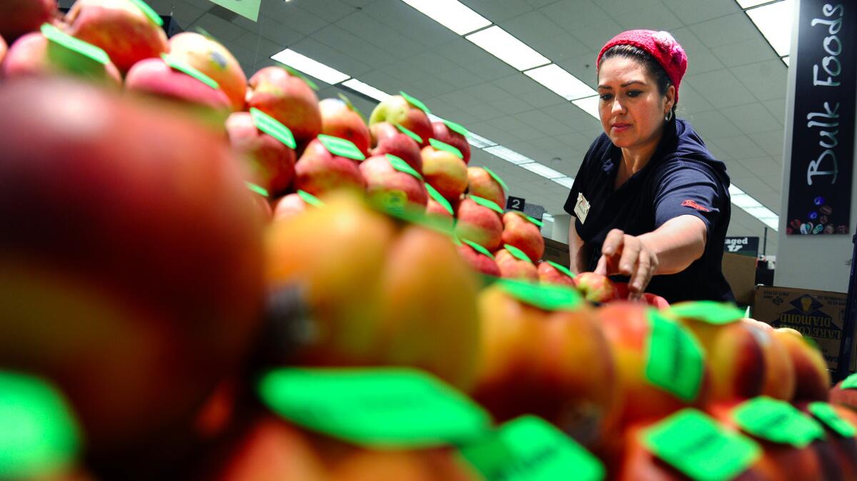 A clerk stocks apples in a Ralphs store in downtown Los Angeles.