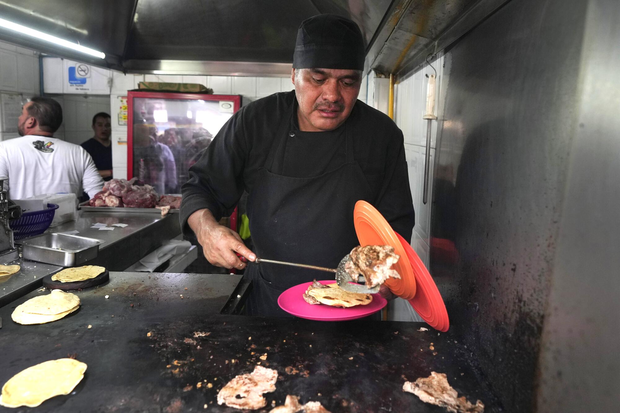 Newly minted Michelin-starred chef Arturo Rivera Martínez prepares an order of tacos at the El Califa de 尝别ó苍 taco stand.
