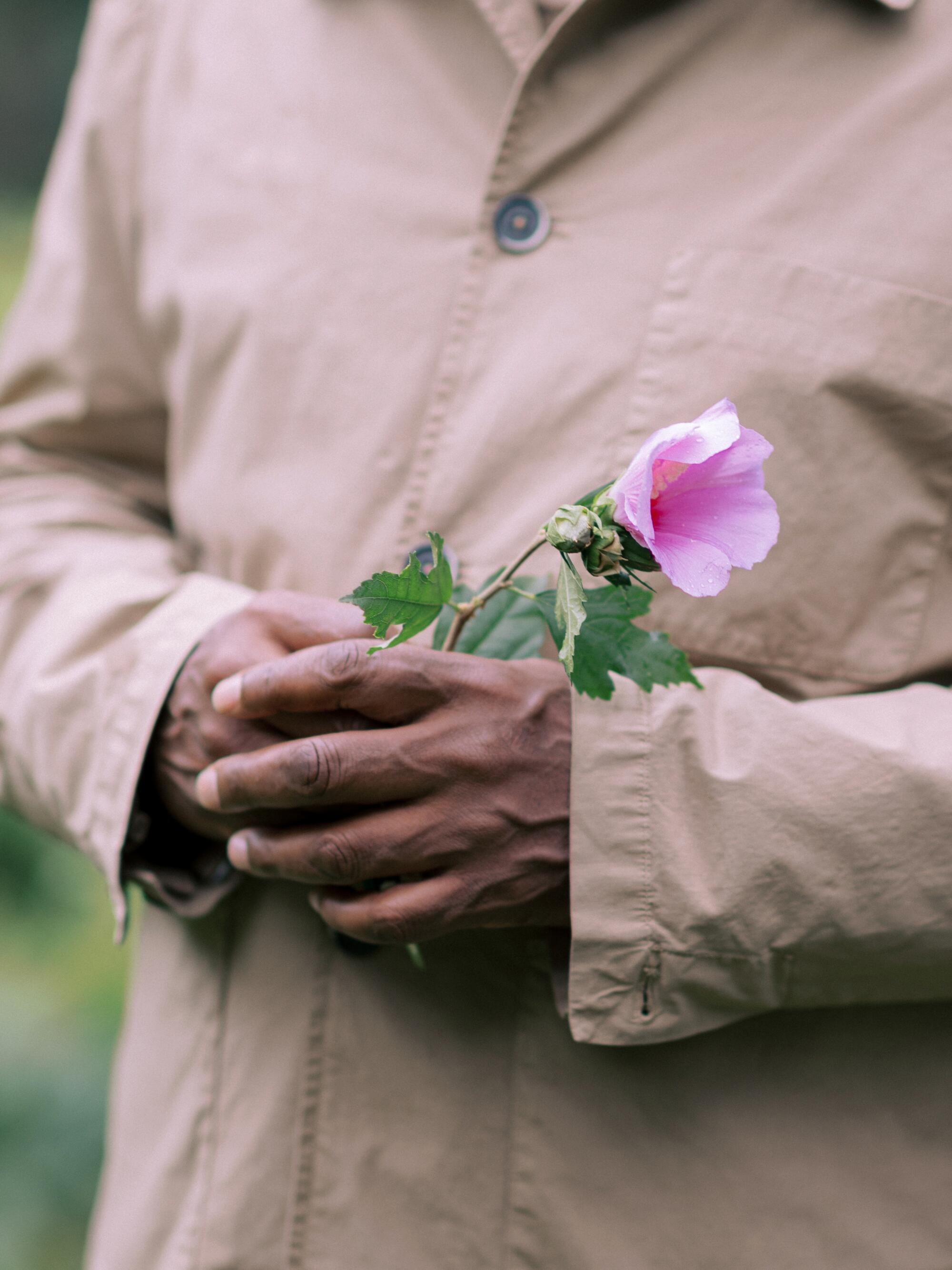 A man holds a pink flower 
