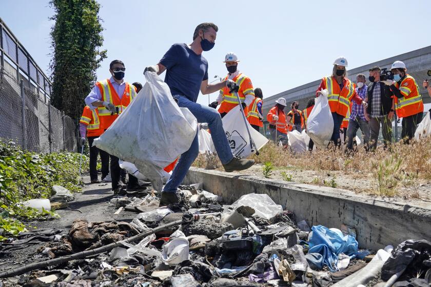 California Gov. Gavin Newsom, center, joins a cleanup effort Tuesday, May 11, 2021, in Los Angeles