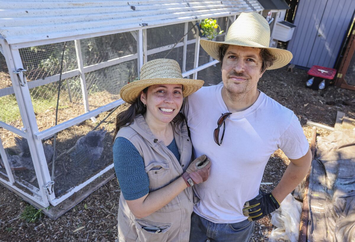  Mark (right) and Kara Stambaugh pose for photos by the chicken coop at their home in La Mesa.