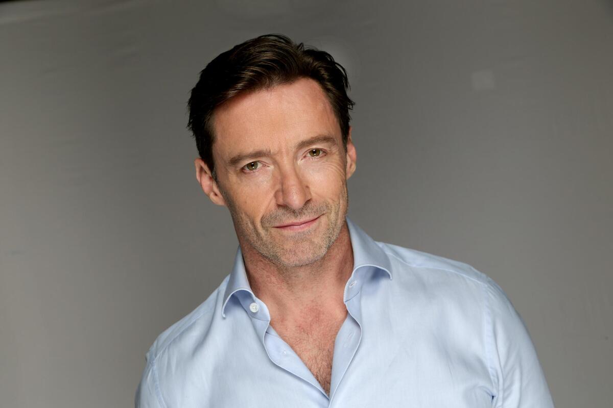 A headshot of actor Hugh Jackman in a blue button-down shirt